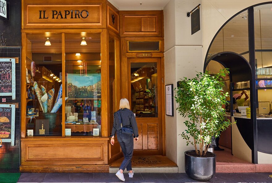 A woman walking into a shop with a wooden exterior.