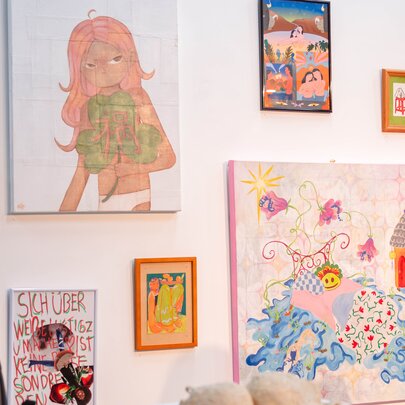 An exhibition of contemporary wall-based artworks in a gallery space, with a person in the foreground.