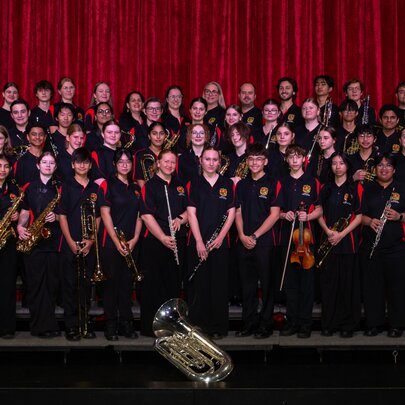 The La Salle College Concert Band, assembled for a group shot on a stage with a red curtain.