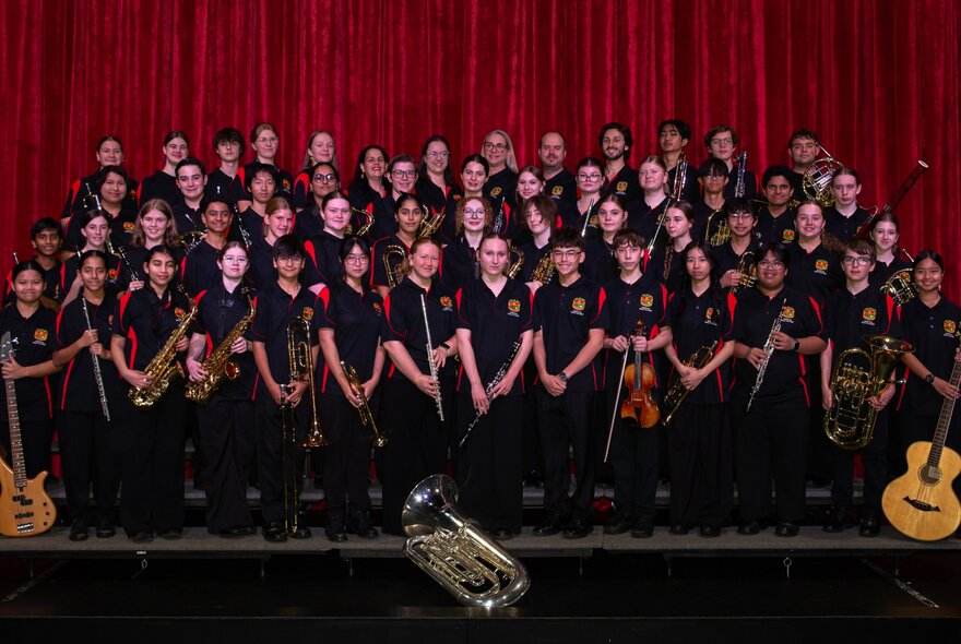 The La Salle College Concert Band, assembled for a group shot on a stage with a red curtain.