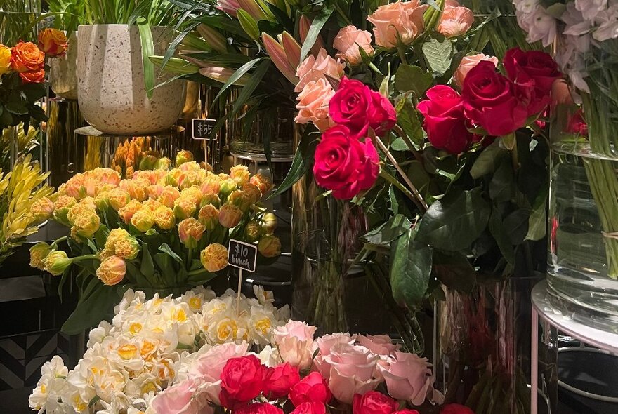 Floristry display of multicoloured roses in large vases.