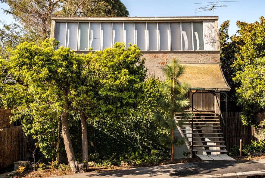 The external facade of Walsh House, with leafy trees in the foreground.