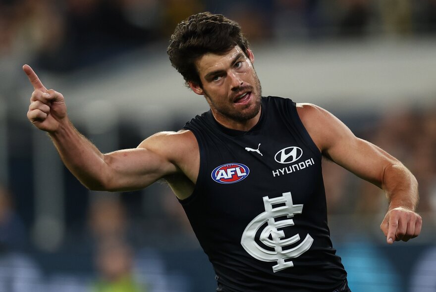 A Carlton AFL player straight after a goal with finger raised in the air. 