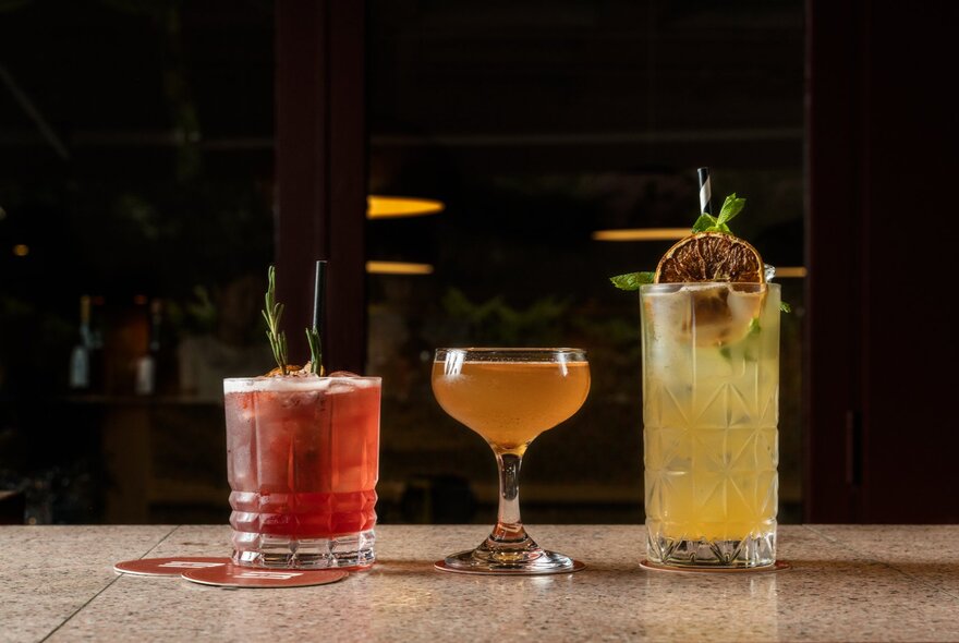 Three cocktails on a bar.