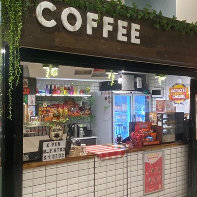 The exterior of a small coffee shop, with products for sale inside.