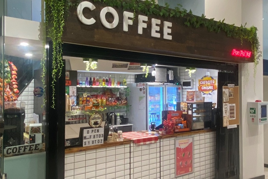 The exterior of a small coffee shop, with products for sale inside.