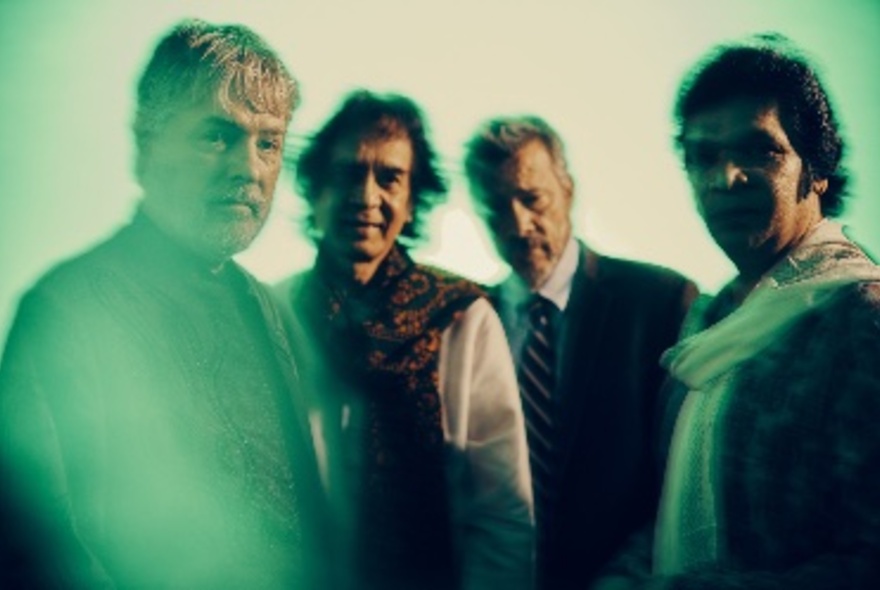 Four musicians staring at the viewer, a filter casting a green wash over their appearance.