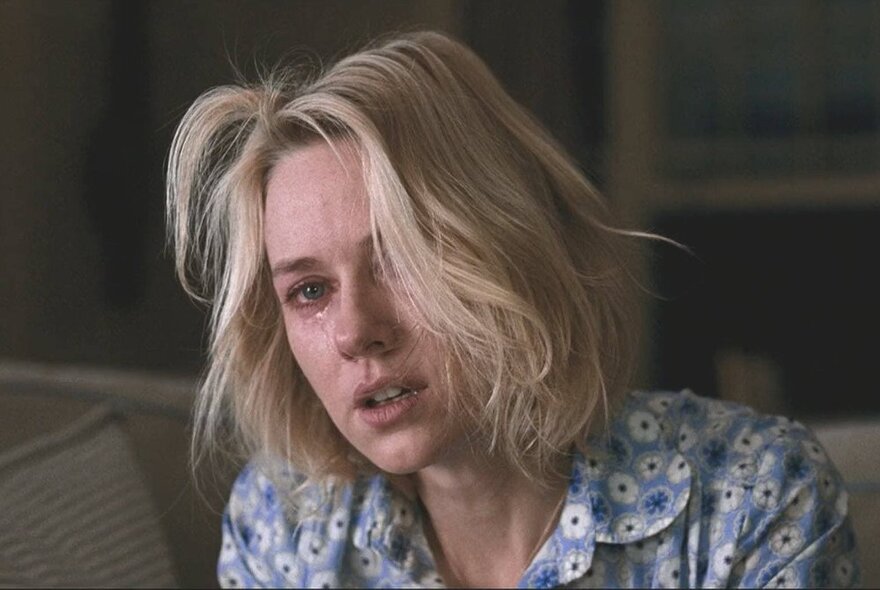 A still image from a film showing a woman with dishevelled blonde hair who has been crying,