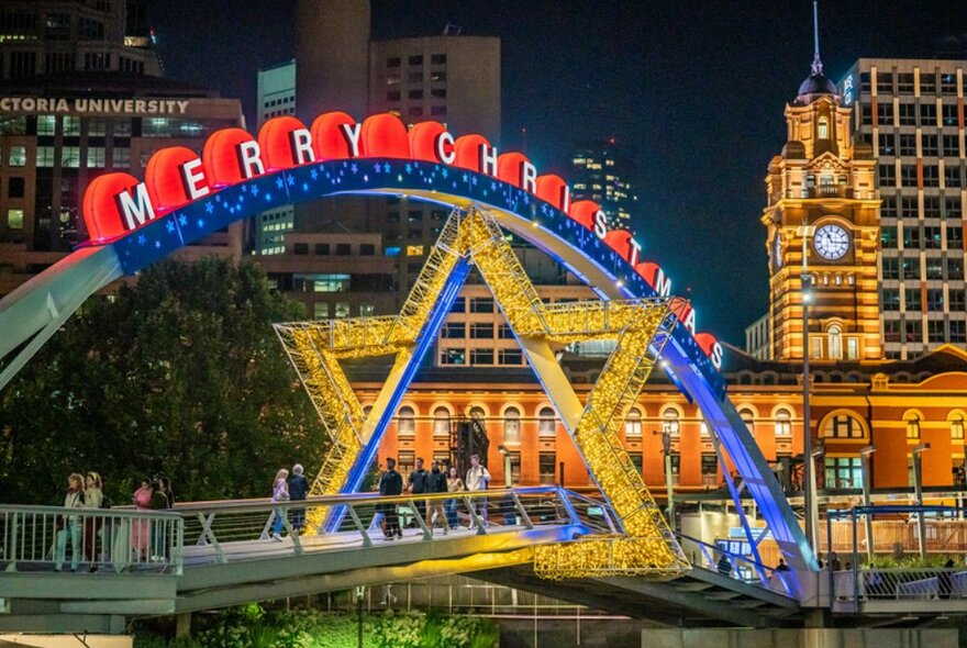 A pedestrian footbridge decorated for Christmas with a star and sign reading 'Merry Christmas'.