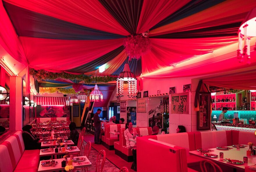 Inside an Indian restaurant with red fabric draped on the ceiling