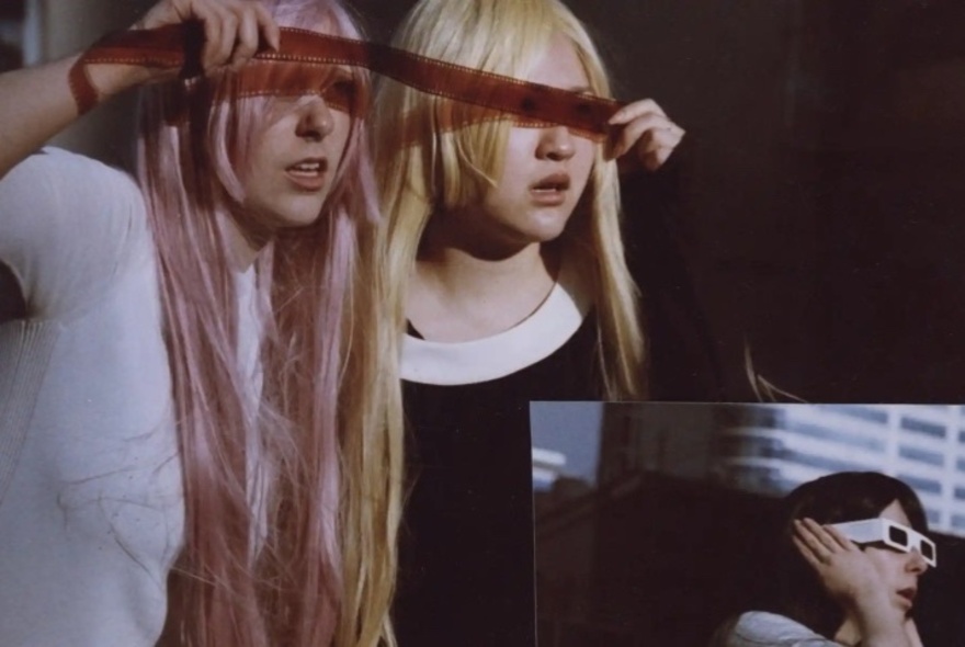 An artwork with two people with long blond hair, looking through a strip of film negative, with an image of a person wearing sunglasses in the corner of the frame.