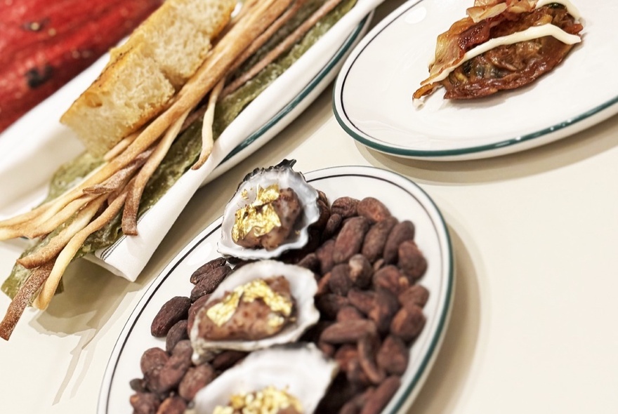 Angled shot of several dishes with cacao beans and oysters. 