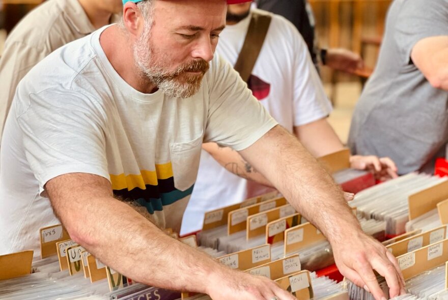 A person flicking through a crate of vinyl records at a record fair market stall.