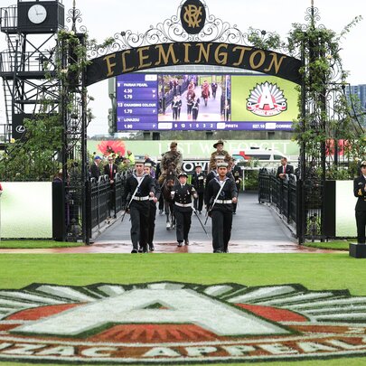 Procession entering Flemington Racecourse under banners to celebrate Anzac Day.