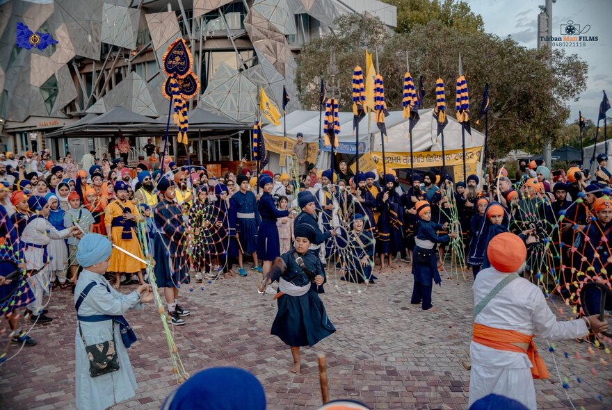 A Sikh festival in Federation Square with people in traditional costumes and flags. 