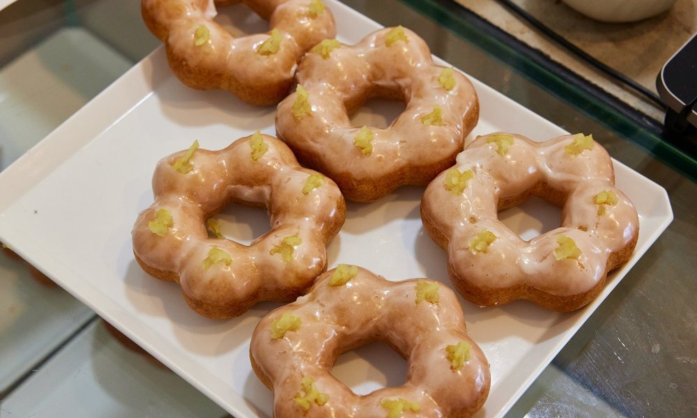 A tray of flower shaped mochi doughnuts with glaze and zest on top.