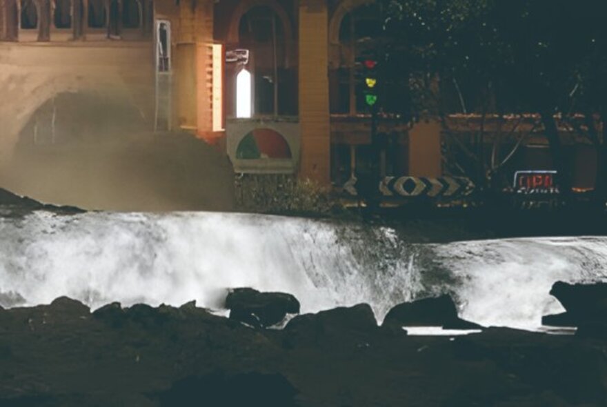 Rocks and waterway in front of city buildings.