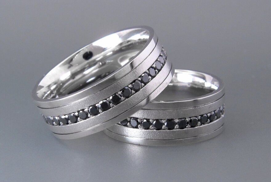 Two silver rings, each encrusted with smaller gemstones.