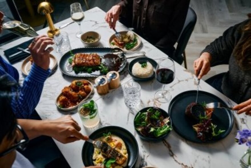 View of a laden table seen from above, with share plates and wine.