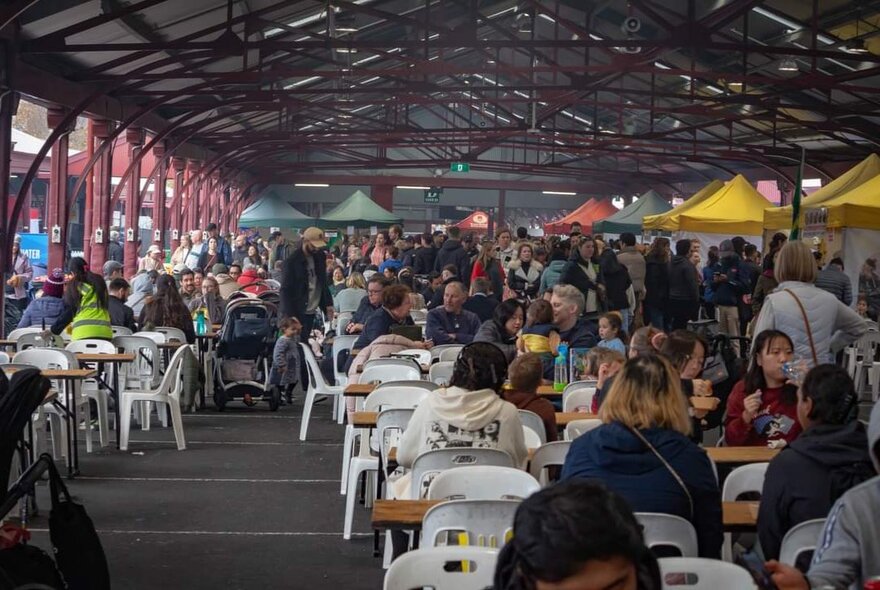 Large crowds gathered inside one of the sheds at Queen Victoria Market, seated at tables or walking around as part of the Taste of Portugal festival.
