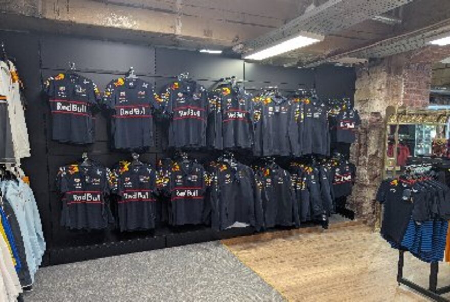 Racks of black F1 branded polo shirts on display in a shop.