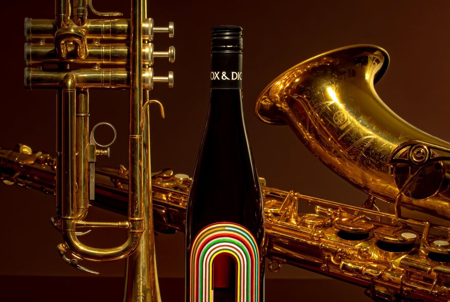 A bottle of wine next to a saxophone.