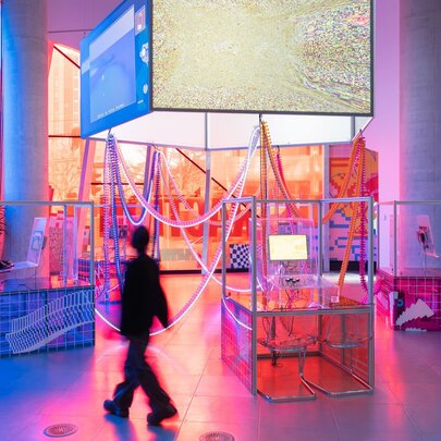 Three people interacting with a neon light installation in a gallery.