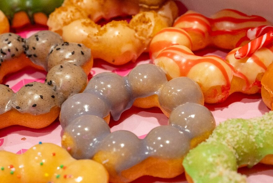 An assortment of mochi donuts with varying glazes and toppings.