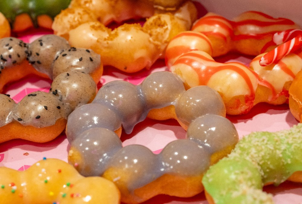 An assortment of mochi donuts with varying glazes and toppings.