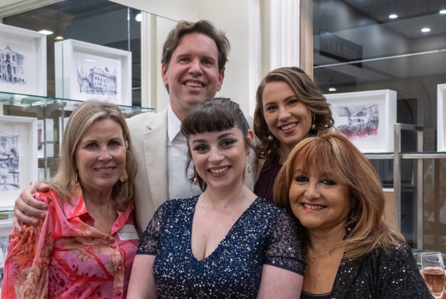 Group of five people smiling and posing for a photo in a gallery shop space.