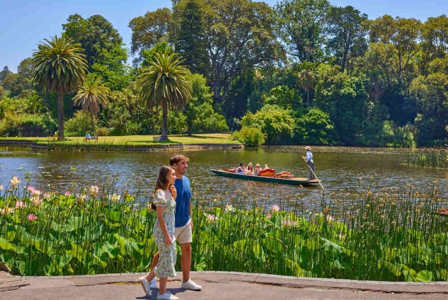 A couple walking beside a pond in the gardens.