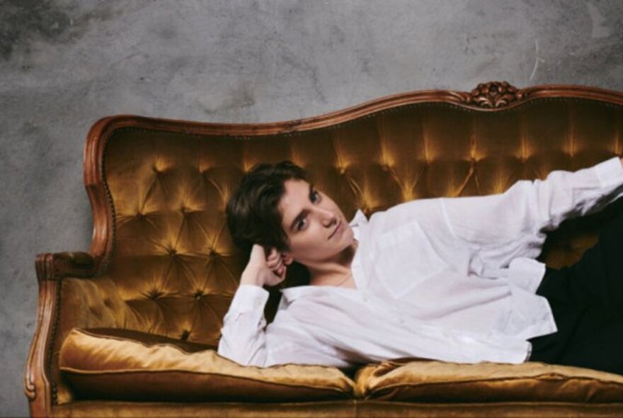 Comedian Sarah Keyworth reclining  on a bronze Baroque sofa.