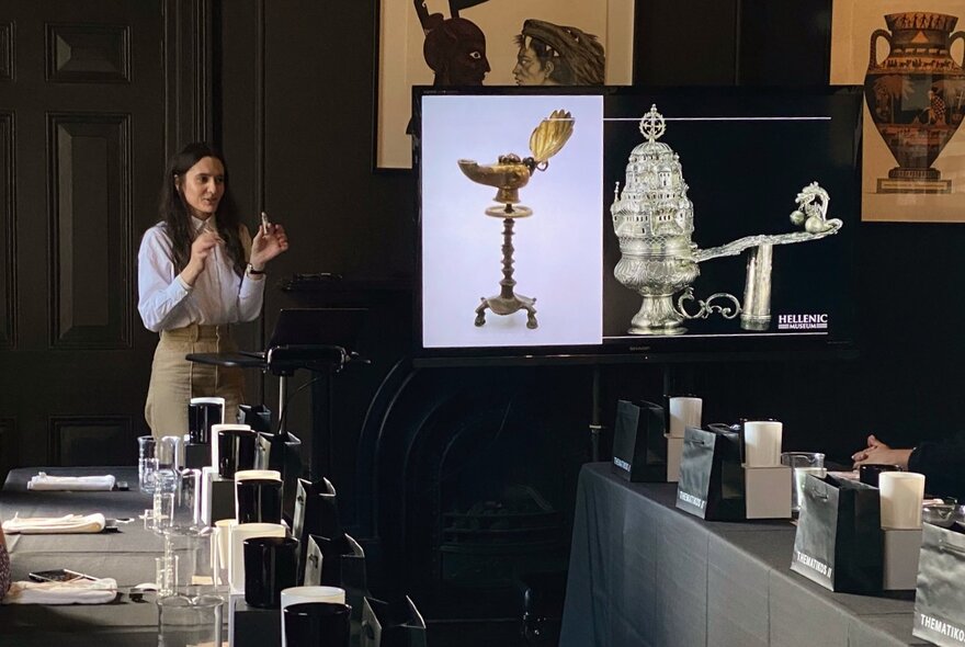 An instructor talking about perfumes in a room  with tables and chairs ready to host a perfume making workshop.