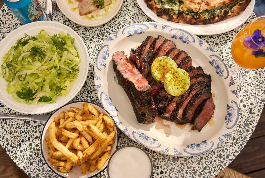 Looking down at plates of Greek food on a tabletop, including chips, salad, and gyros.