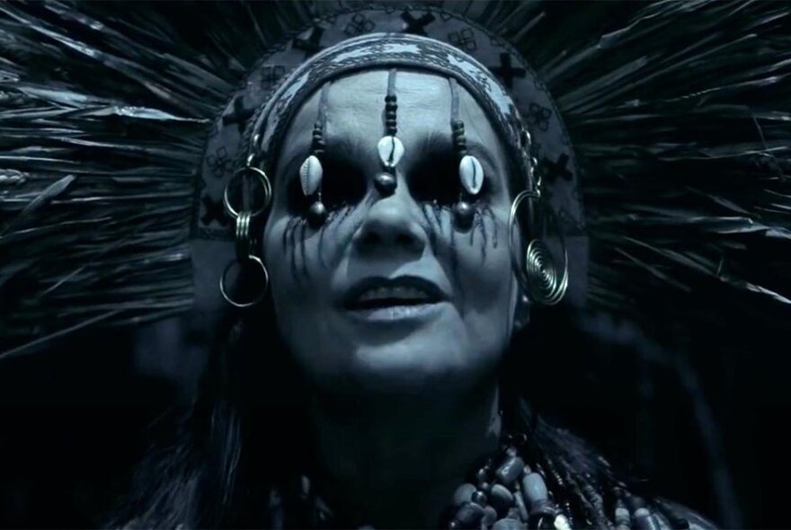 Artist Björk wearing a spiky headdress and ornaments over her eye; black and white image.