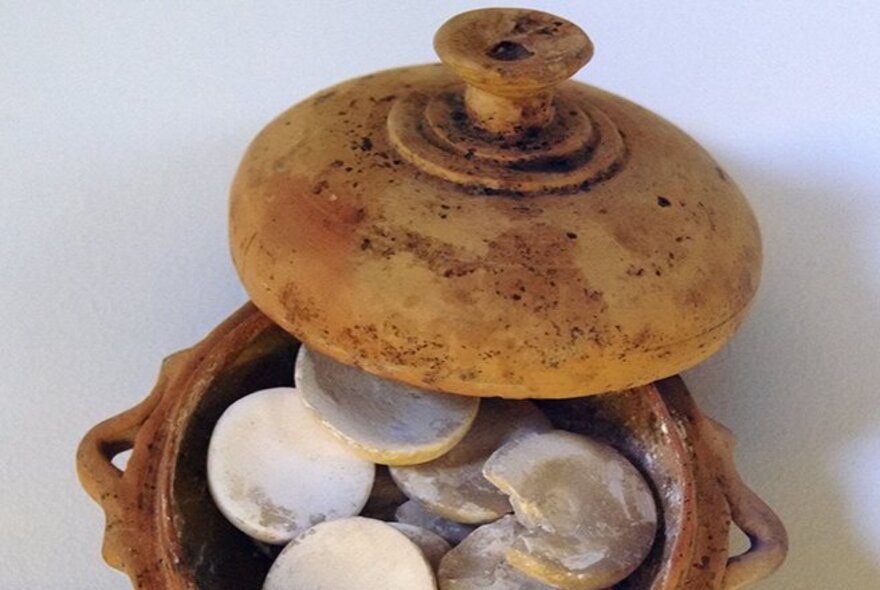 An ancient artefact with a lid, filled with stone discs. 