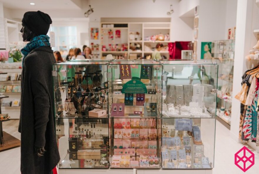 Retail space showing glass display cubes, and shelves of items against a white wall.