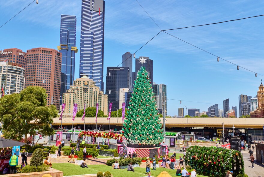 A giant Christmas Tree at Federation Square, with the sky and city buildings in the background.
