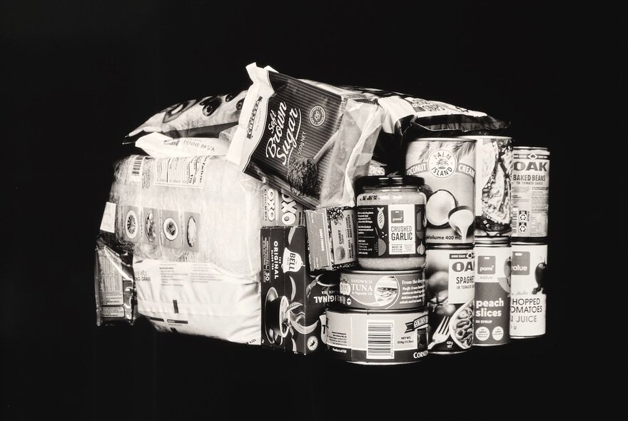 A black and white photograph of stacked basic grocery items, as art.