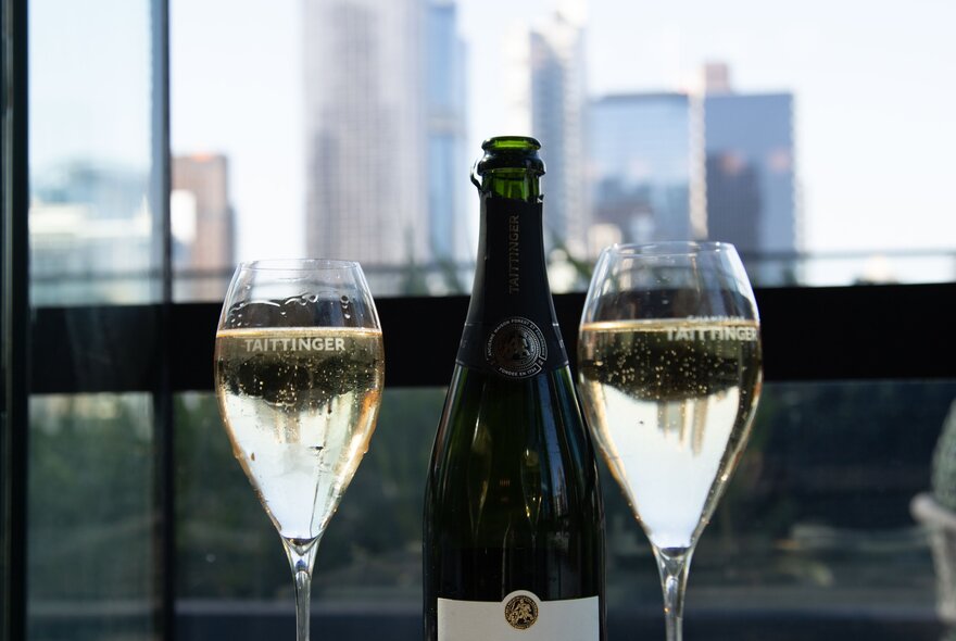 Two glasses of sparkling wine with blurred city views.