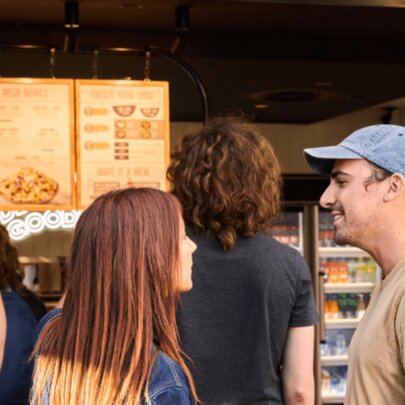 Two people standing in a queue for fast food.