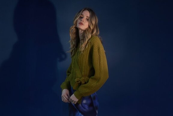 A model posing in a cable knit olive green wrap cardigan.