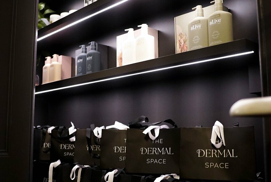 High-end skindcare products and black shopping bags displayed on black shelves.