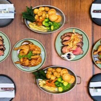 Several dishes of food on a restaurant table, including roast meat and vegetables.