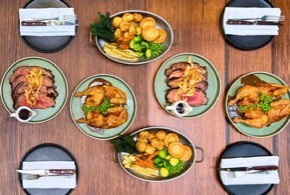 Several dishes of food on a restaurant table, including roast meat and vegetables.