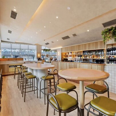 Interior view of  brightly lit cafe with seating areas and a bar.