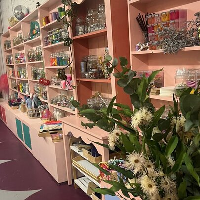 Interior of Whimsy Disco with pink shelves full of small objexts and flowers in the foreground. 