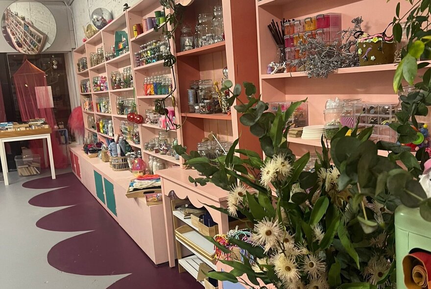 Interior of Whimsy Disco with pink shelves full of small objexts and flowers in the foreground. 