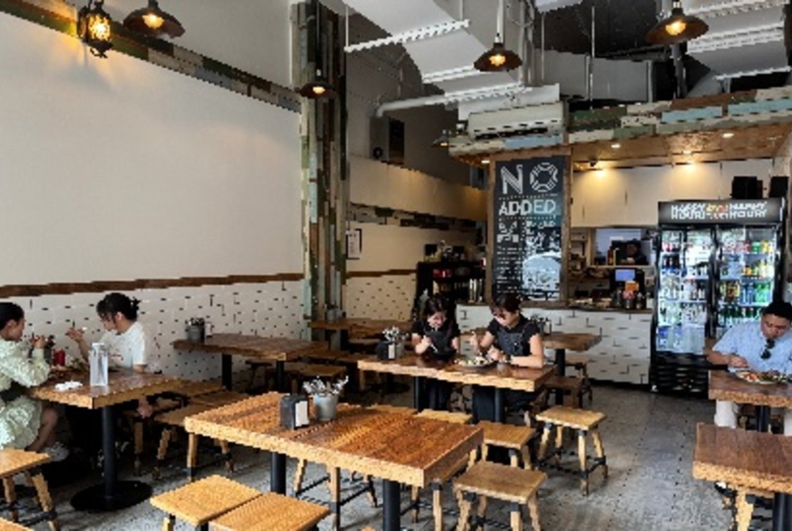 The interior of a small restaurant with mostly empty tables.