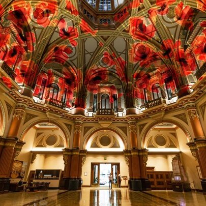 The grand, ornate domed interior of 333 Collins Street building, with a red poppy projection on the ceiling.
